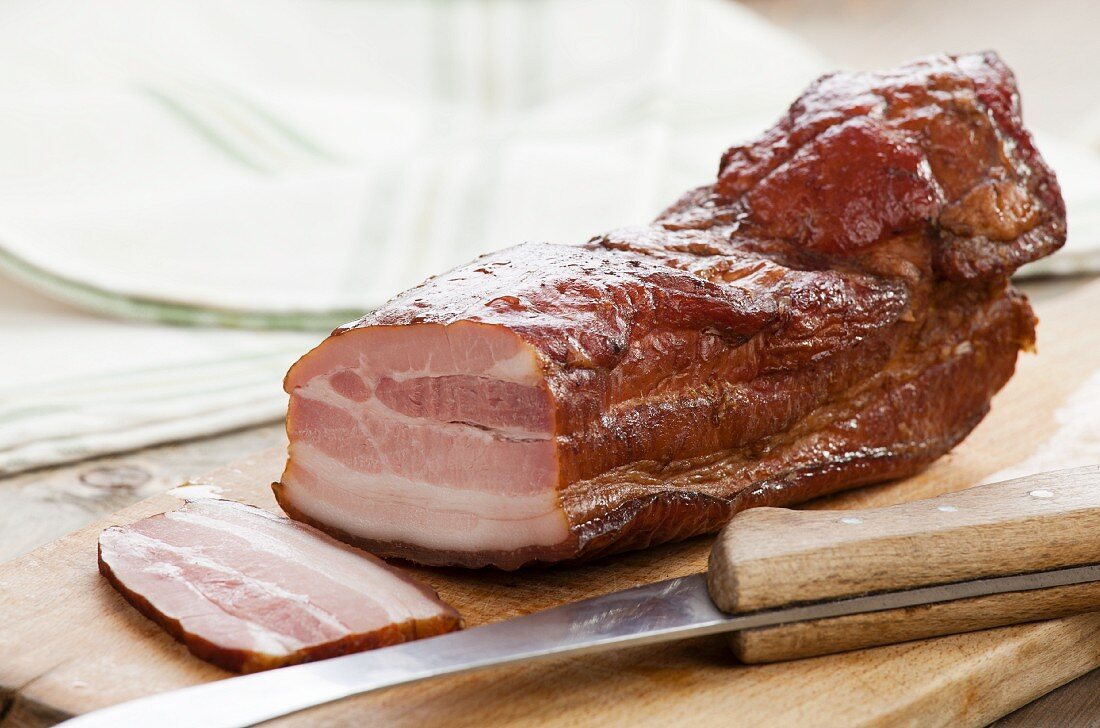 Smoked bacon on a wooden board with a knife