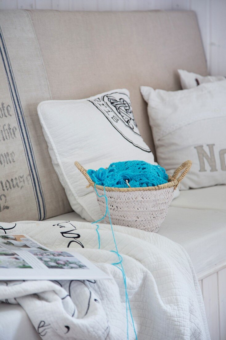 Small basket of crochet supplies with pale blue wool on bench