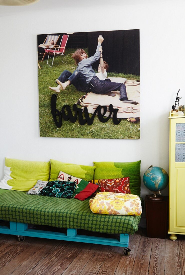 DIY sofa made from pallets below large picture on wall
