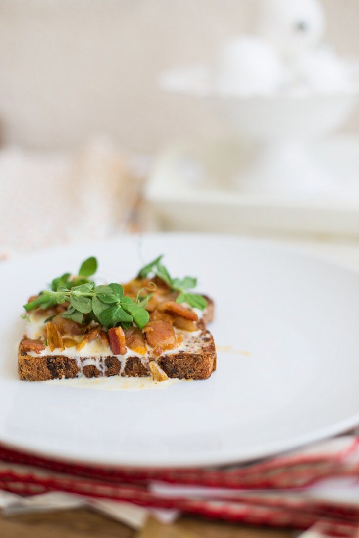 Vollkornbrot mit geschmolzenem Ziegenkäse, Speck, Zwiebeln und Brunnenkresse