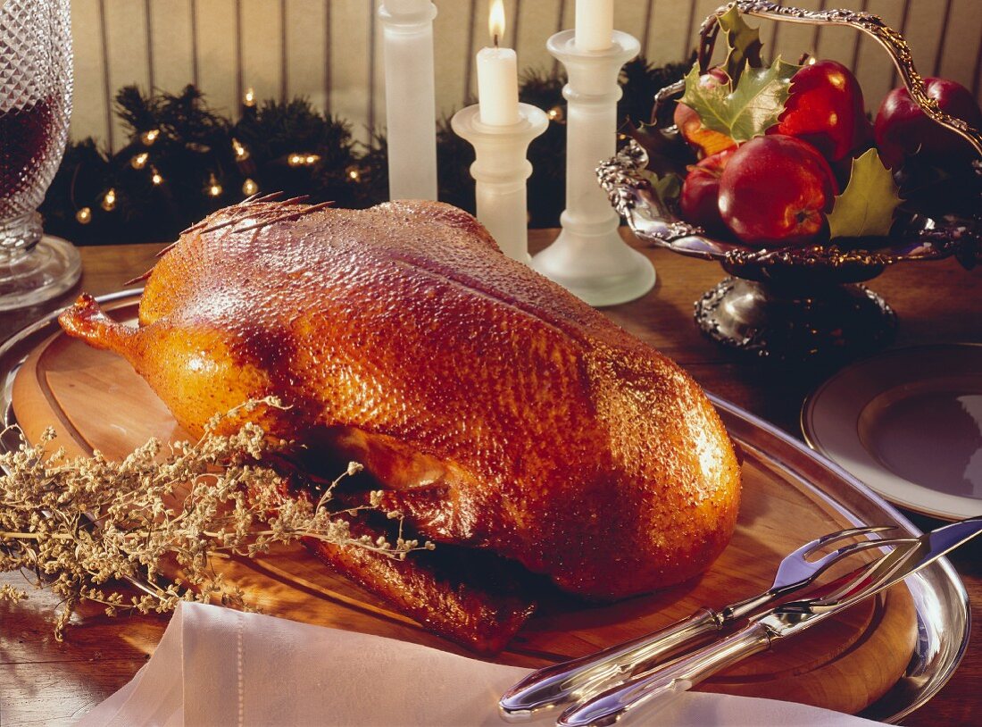 Goose with dumpling stuffing on a wooden board with a carving set