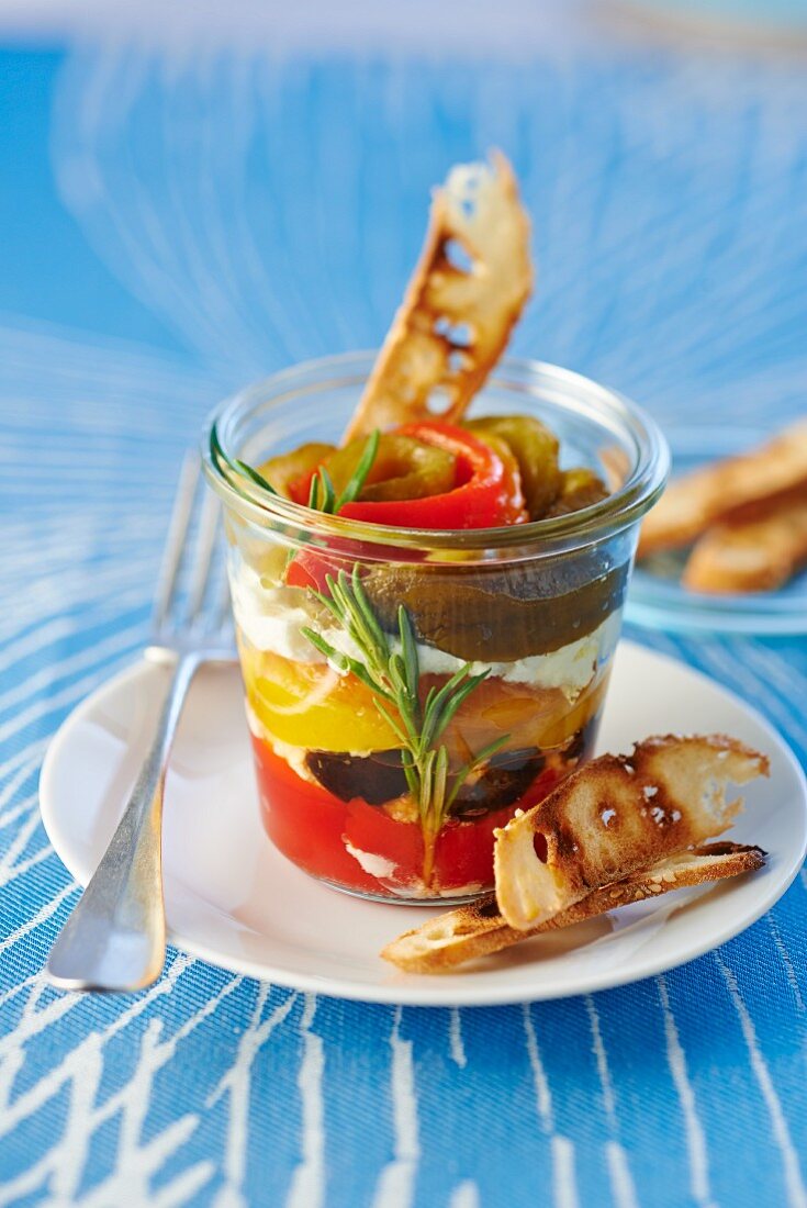 Paprika mit Oliven und Käsecreme im Glas, dazu Brotchips