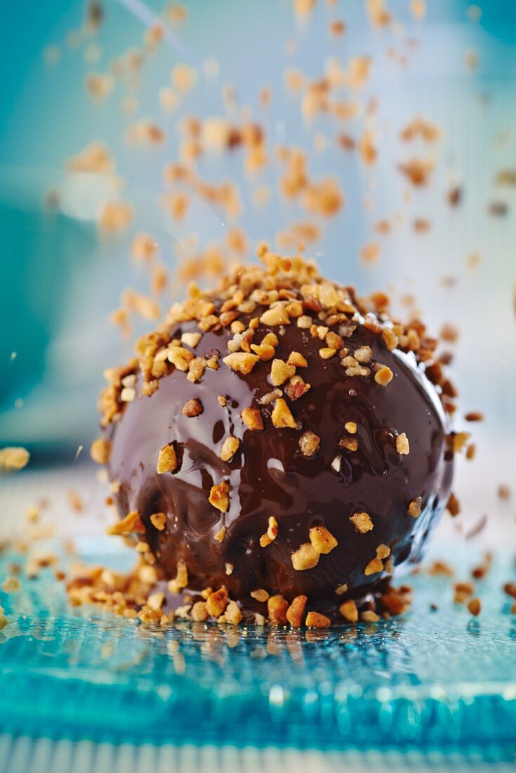 A chocolate-nut praline being sprinkled with brittle