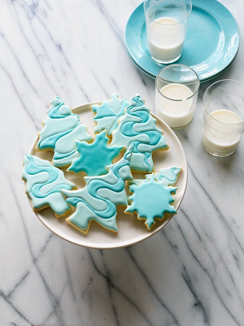 Christmas biscuits with blue icing and three glasses of milk