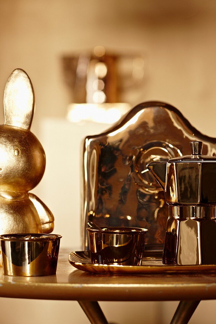 Chrome espresso pot and dish next to gilt rabbit on side table