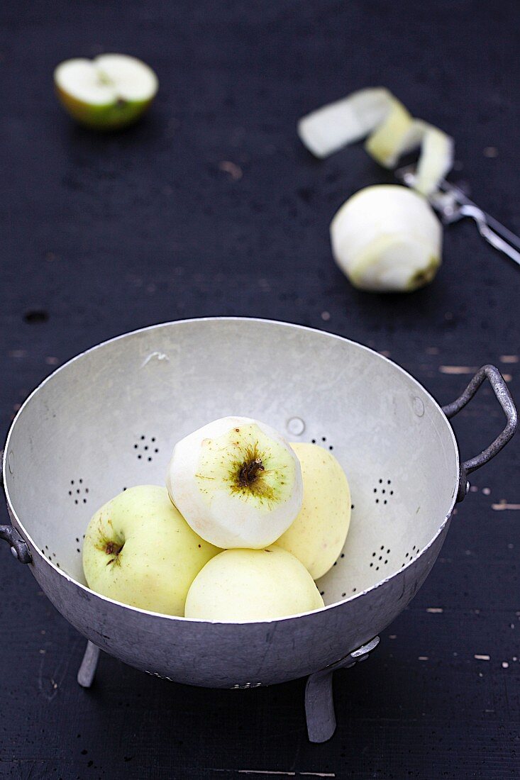 White Transparent apples, partially peeled, in a colander