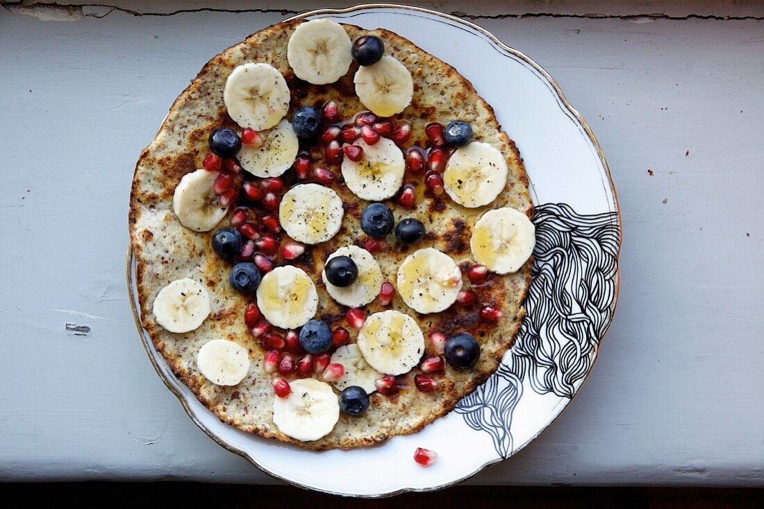 Almond pancake with bananas, pomegranate seeds and blueberries