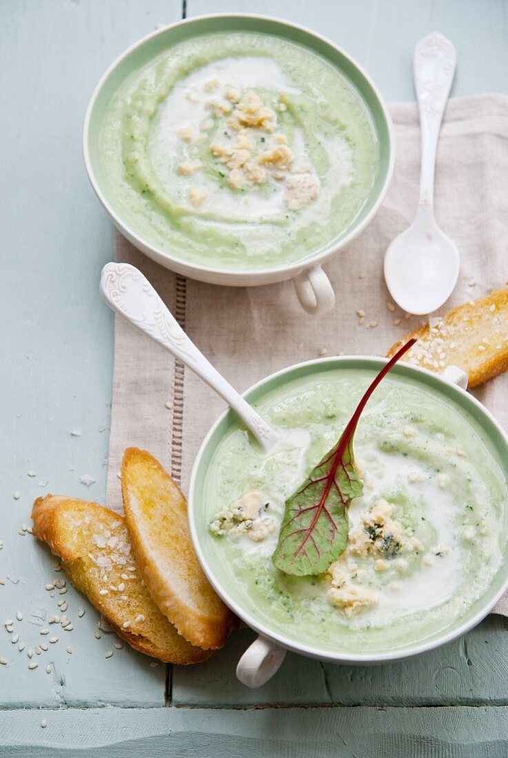 Cream of broccoli soup with blue cheese topped with a beetroot leaf and served with sesame toast