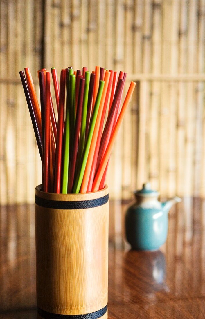 Colourful chopsticks in a bamboo container on a table in a restaurant
