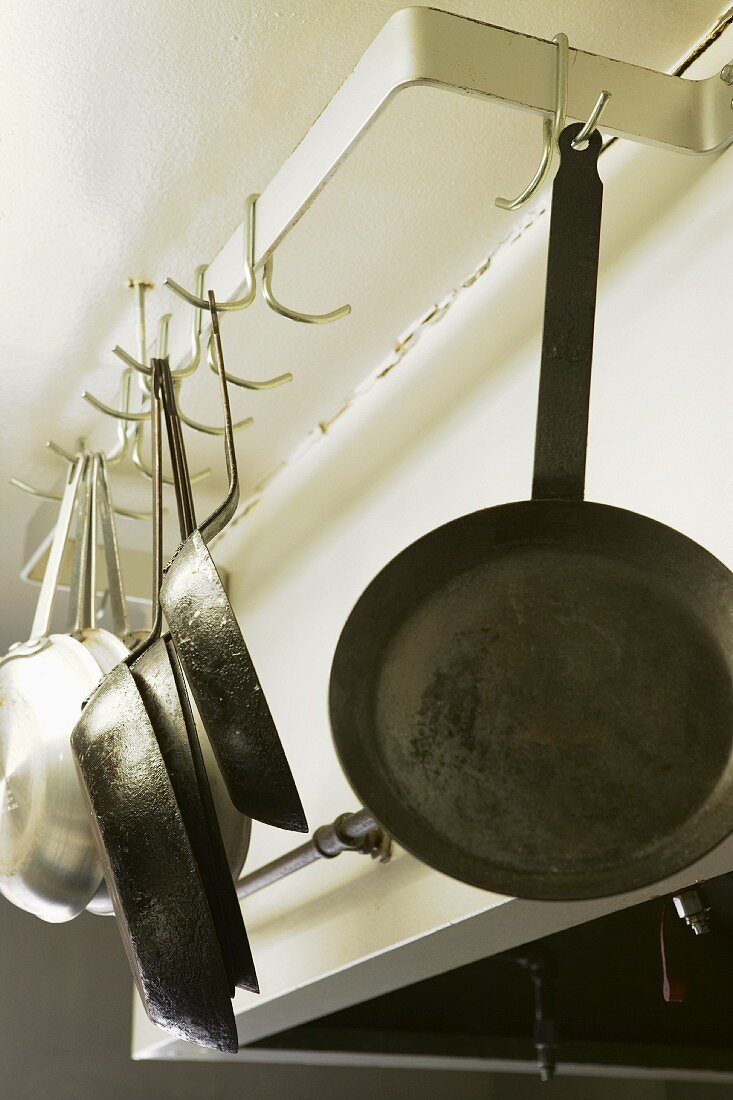An Haken hängende Metallpfannen in einer Restaurantküche