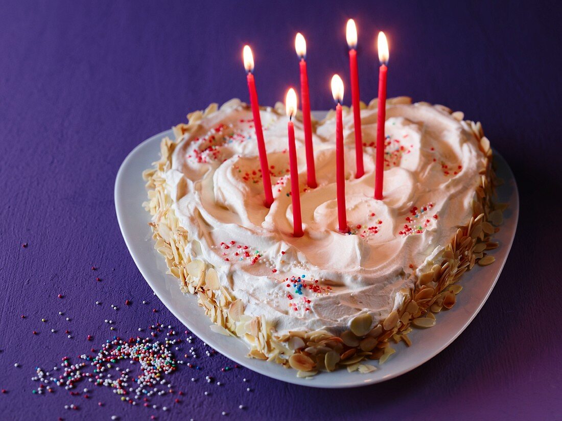 A heart-shaped cake with burning candles for birthday
