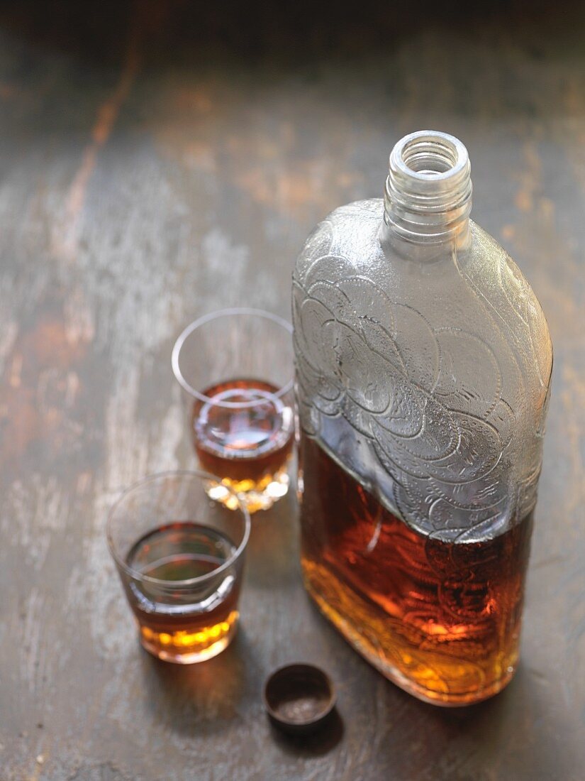 An antique bottle of whisky and two glasses