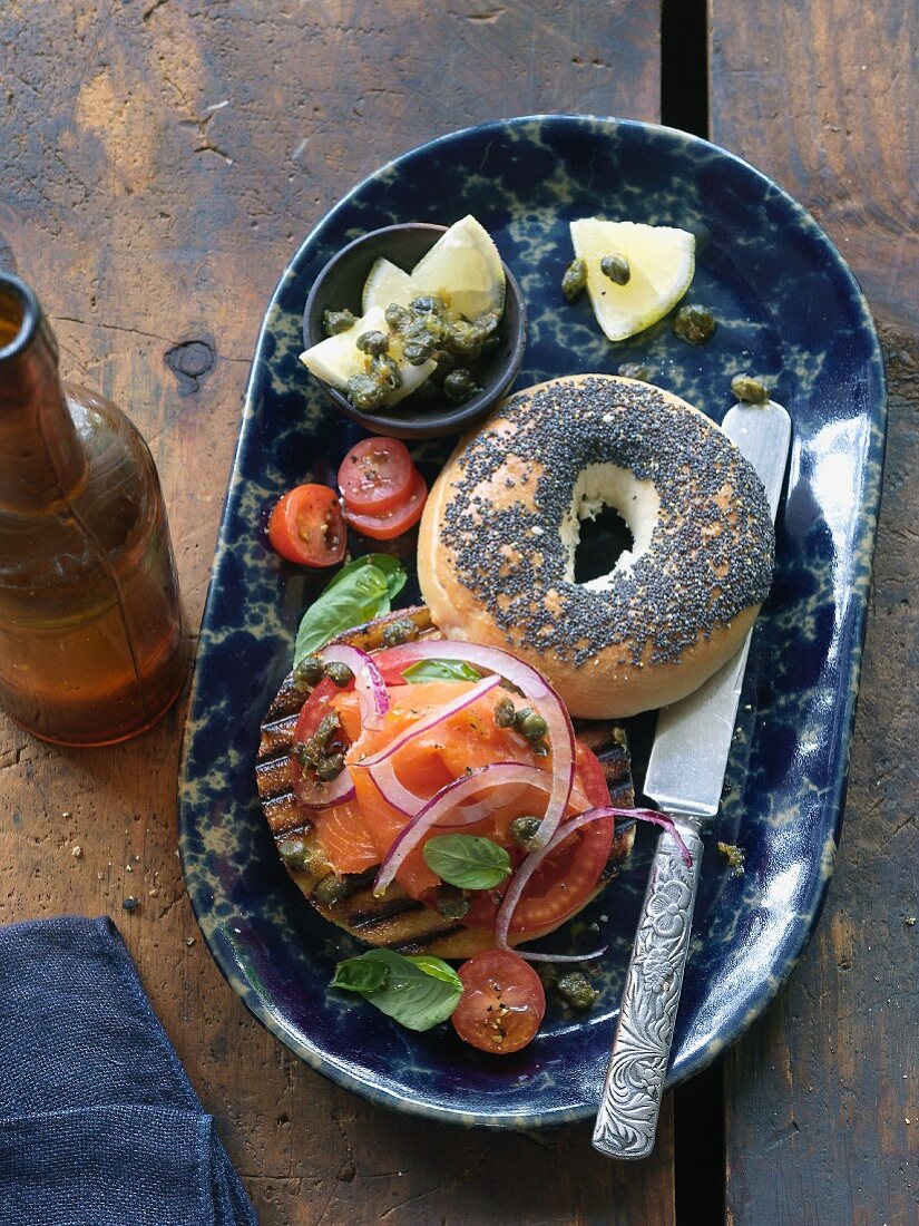 A poppyseed bagel with smoked salmon, capers and onions