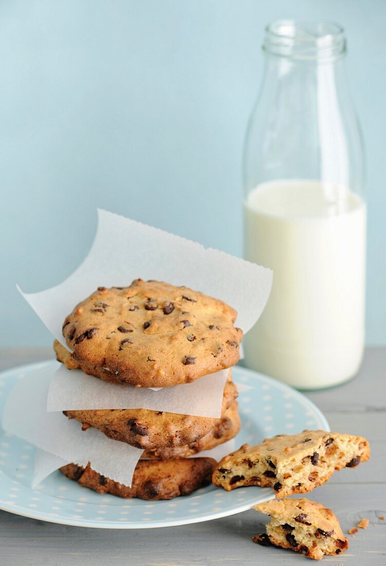 A stack of homemade hazelnut chocolate chip cookies with a bottle of milk