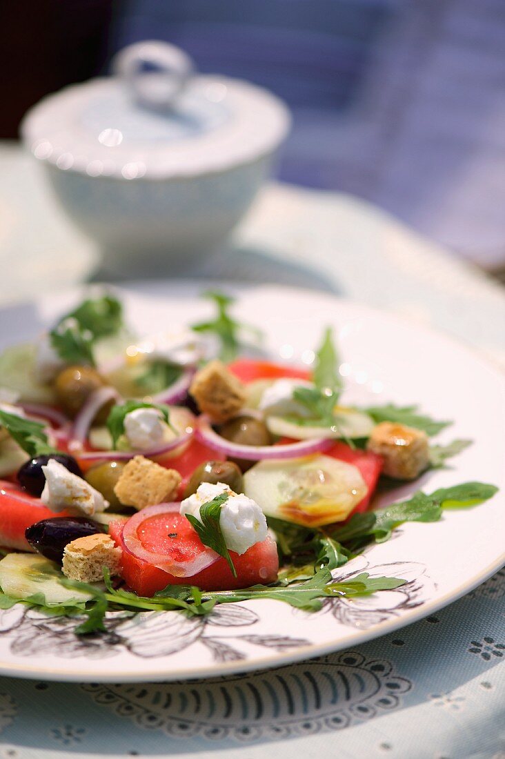 Melonen-Ziegenkäse-Salat mit Oliven, Croûtons, Gurke und Rucola