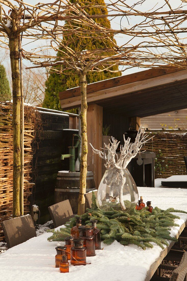 Snow-covered table decorated with fir branches on terrace