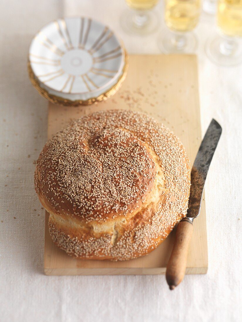 Sesame seed challa (Jewish bread) with a knife on a chopping board