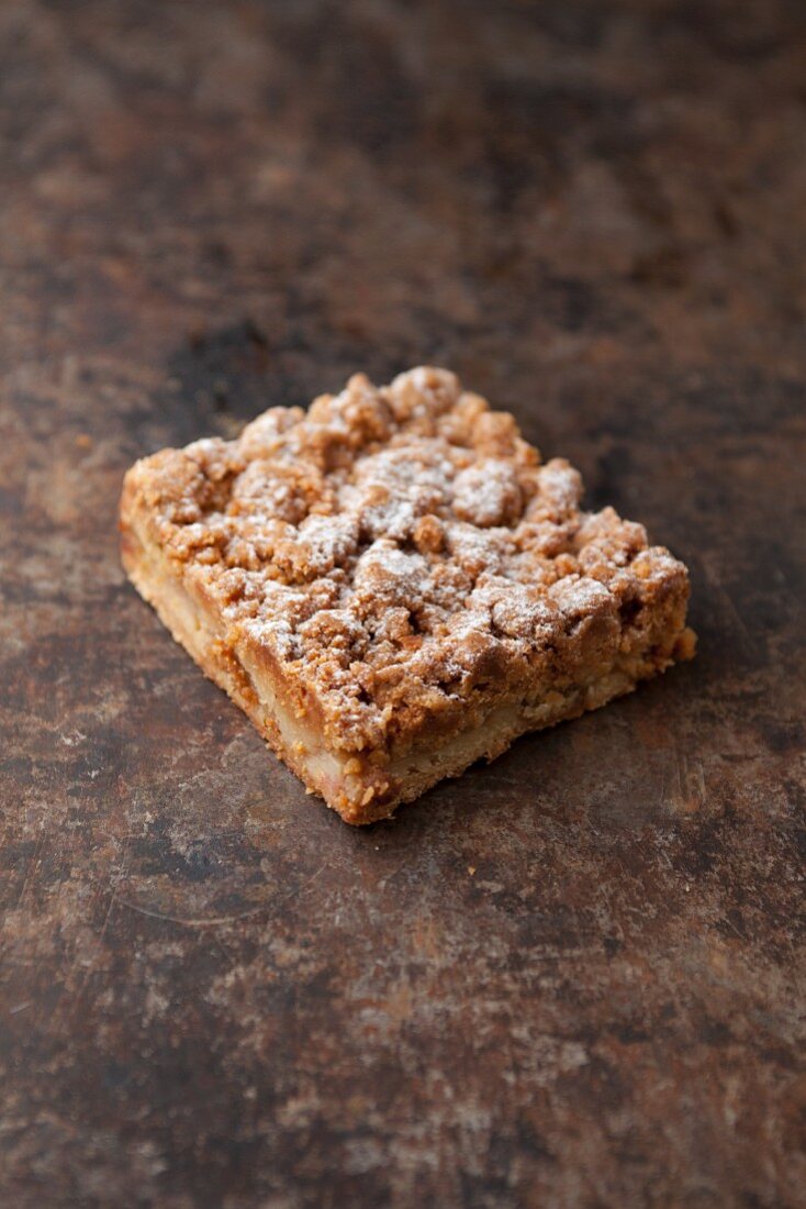 A slice of apple crumble cake on a baking tray