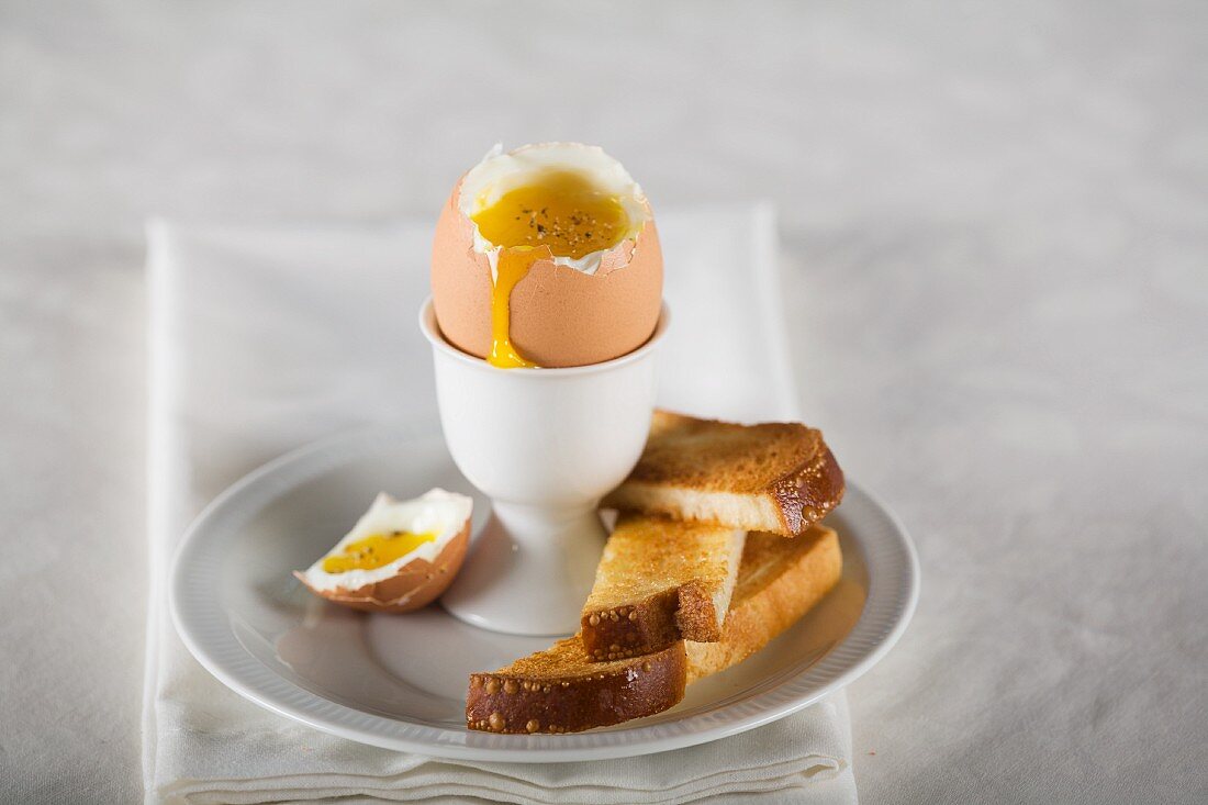 A soft-boiled egg in an egg cup with soldiers