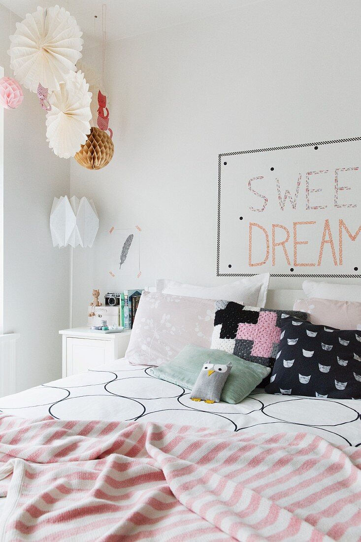 Patterned scatter cushions and striped blanket on double bed in romantic bedroom