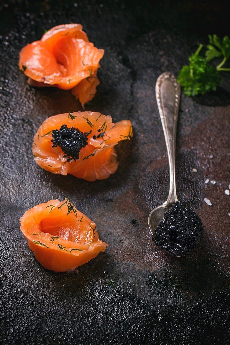 Schwarzer Kaviar auf Lachsröllchen und Löffel