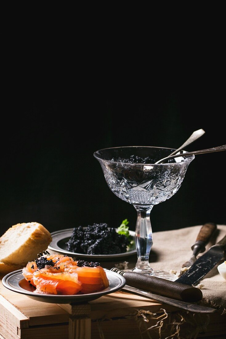 Schwarzer Kaviar in Kristallschale, auf Zinnteller und Lachsröllchen