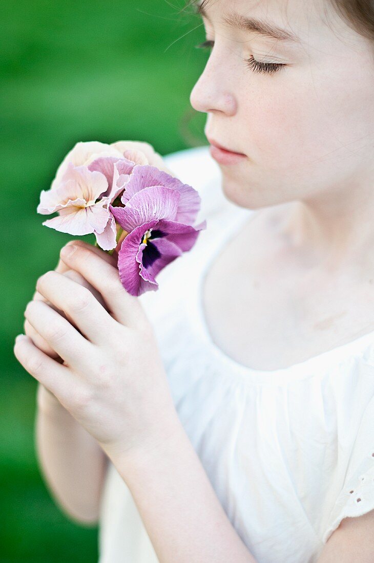 Mädchen riecht an zarten Stiefmütterchenblüten