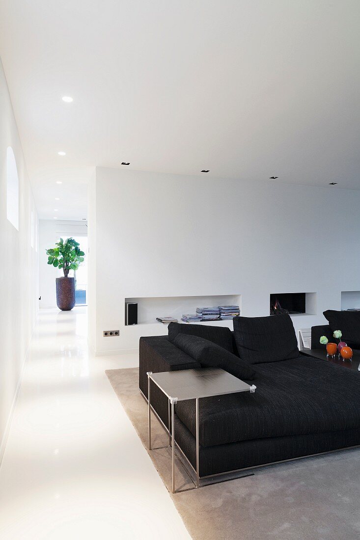 Delicate side table next to black sofa in front of niches in wall in modern interior