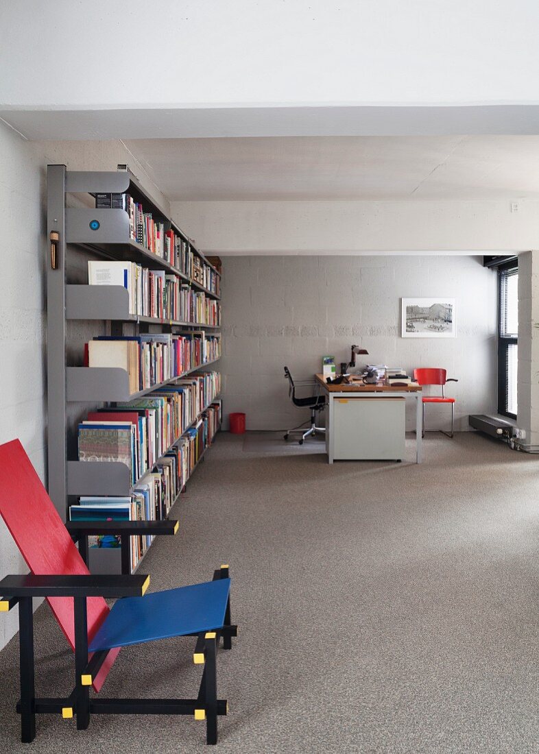 Designer chair next to simple metal shelves and desk in background