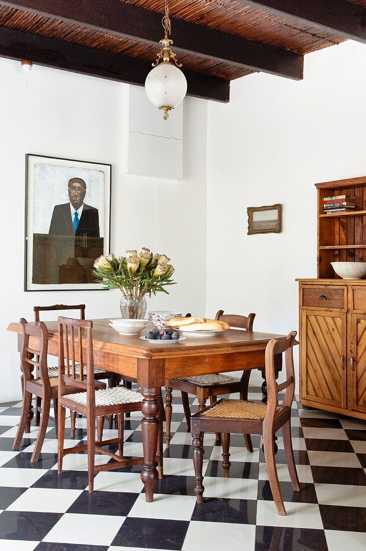 Dining area with antique chairs and table on chequered floor in rustic interior