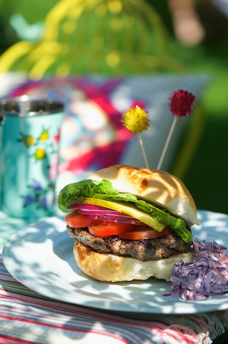 A hamburger and red cabbage coleslaw at a summer party
