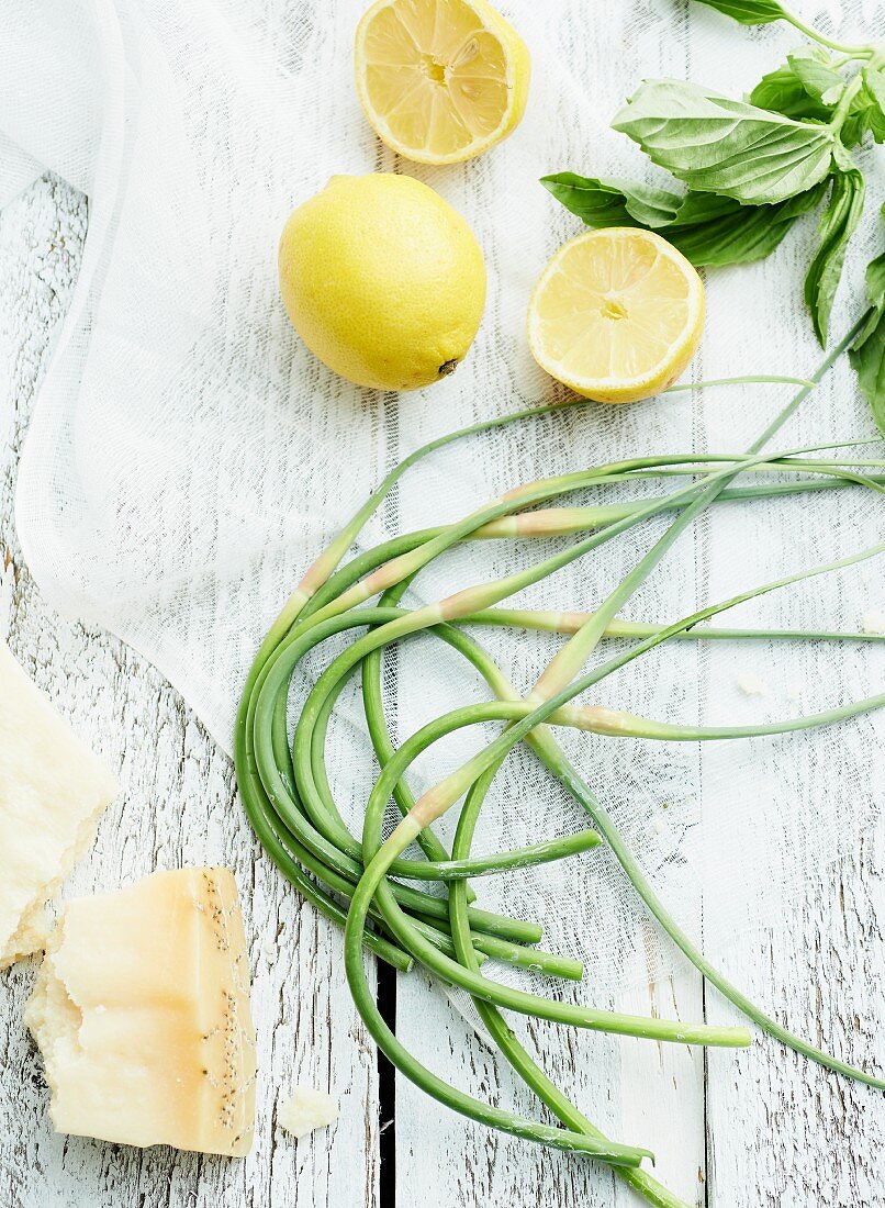 Garlic chives, lemons and Parmesan on wooden table