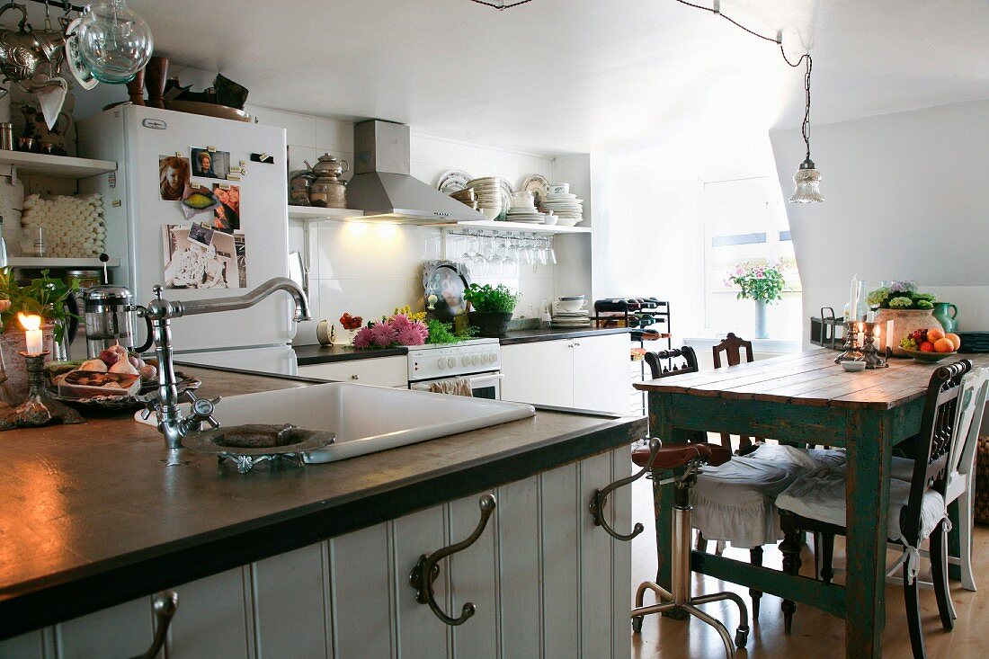 Counter with integrated sink on wooden base unit with hooks in front of dining area in simple kitchen