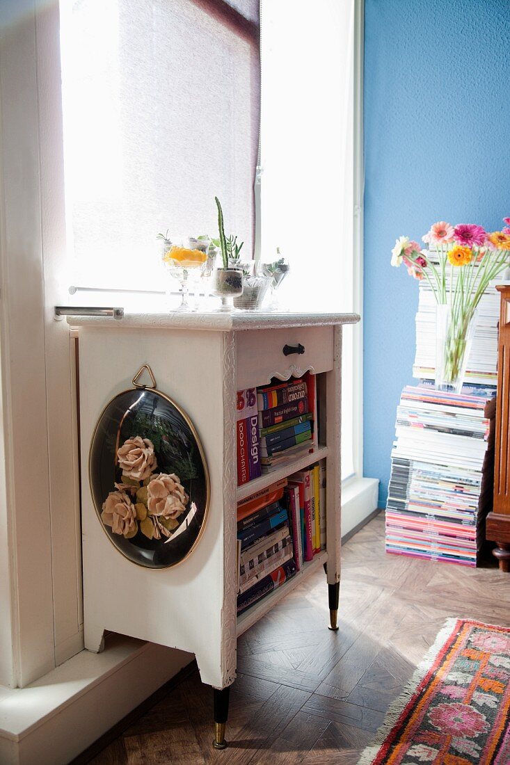 Books in old bedside cabinet with sawn-off legs on plinth