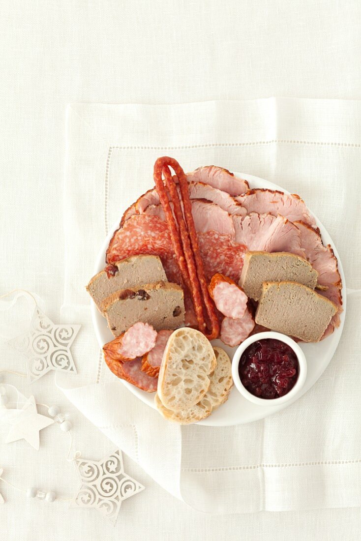Fleisch- und Schinkenplatte mit Wurst, Kabanossi, Schweinepastete, Weißbrot und Preiselbeermarmelade (weihnachtlich)