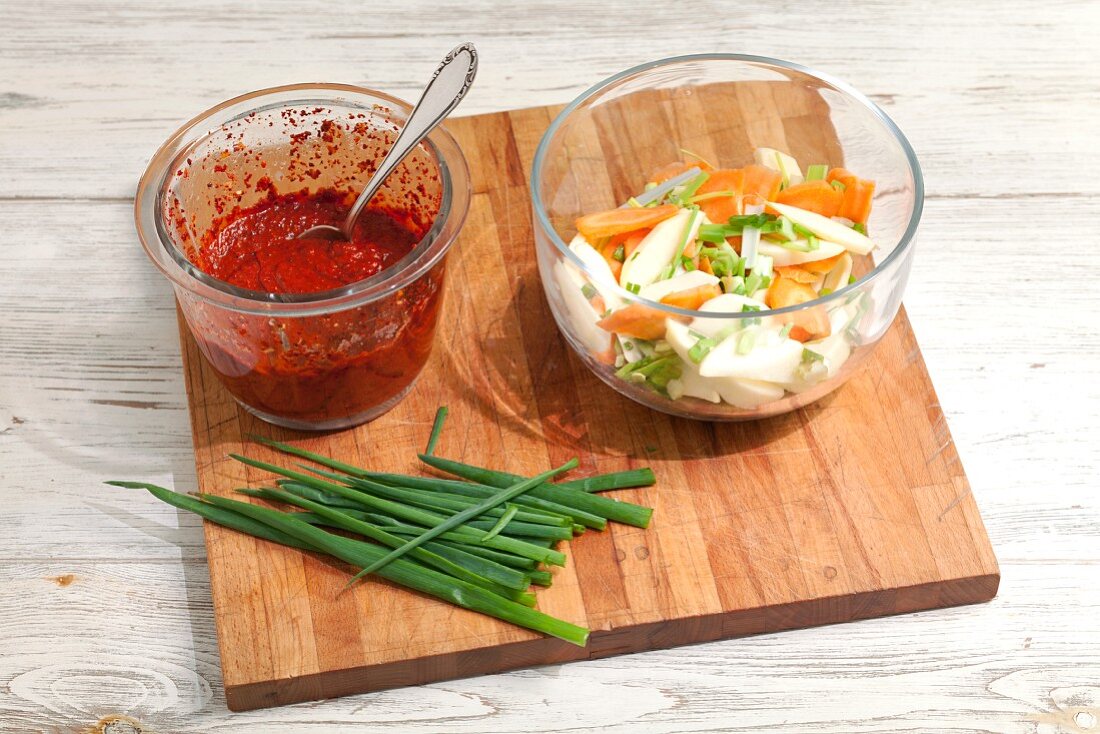 Chilipaste, geschnittenes Gemüse und Frühlingszwiebeln auf Schneidebrett