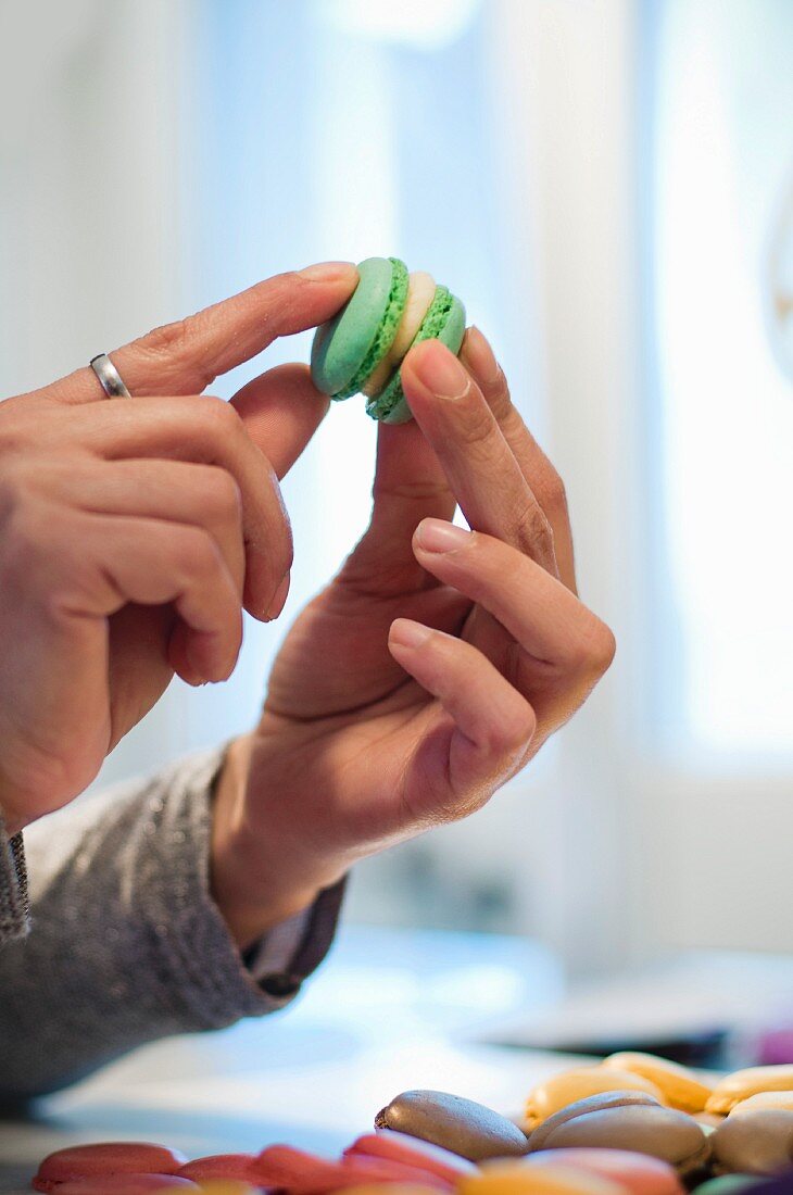 A woman pushing two halves of a cream-filled macaroon together