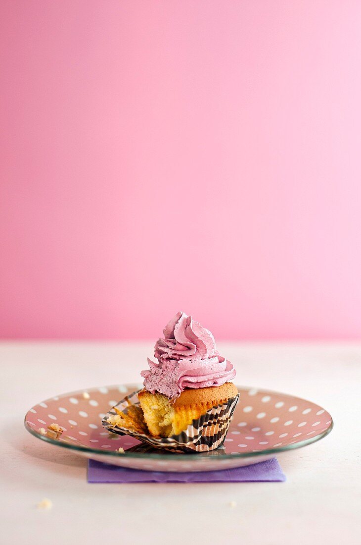Cupcake mit rosa Creme, angebissen