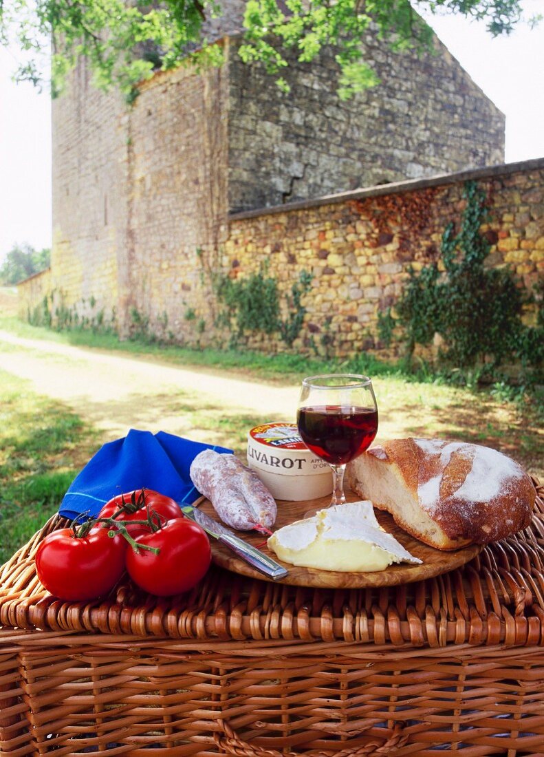 A picnic of bread, cheese, tomatoes and red wine on a hamper in the Dordogne, France