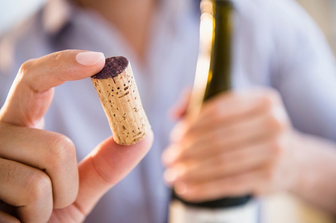 A man holding a red wine cork