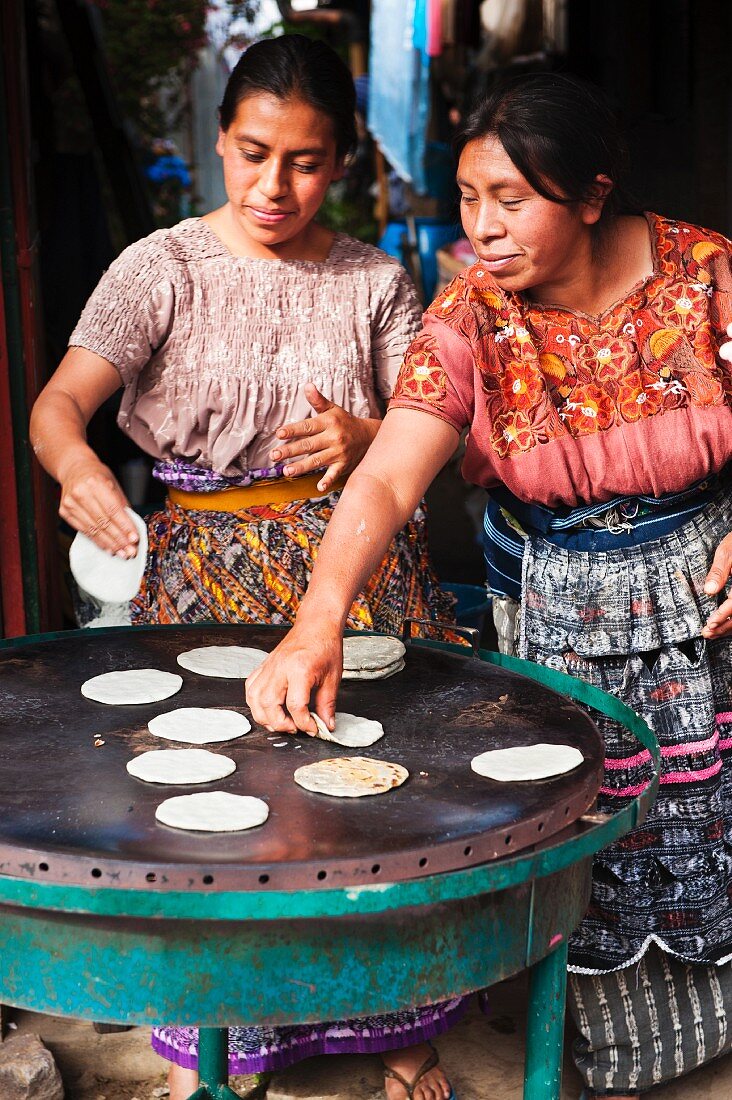 Maya-Frauen backen Tortillas auf dem Markt in Santiago Sacatepequez, Guatemala, Mittelamerika