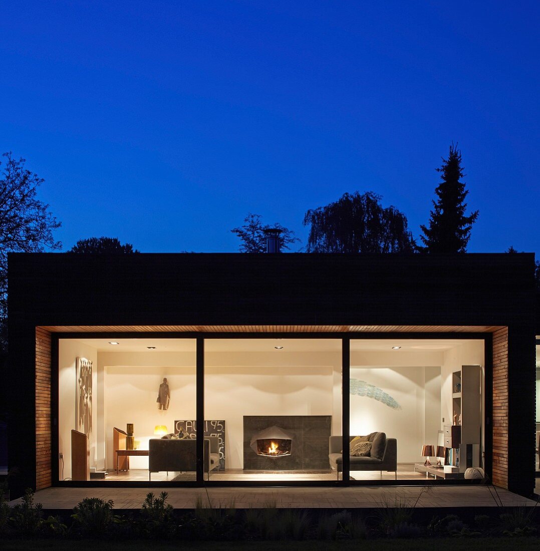 Point 7, Winchester, United Kingdom. Architect: Dan Brill Architects, 2014. View into illuminated living room of contemporary house at dusk