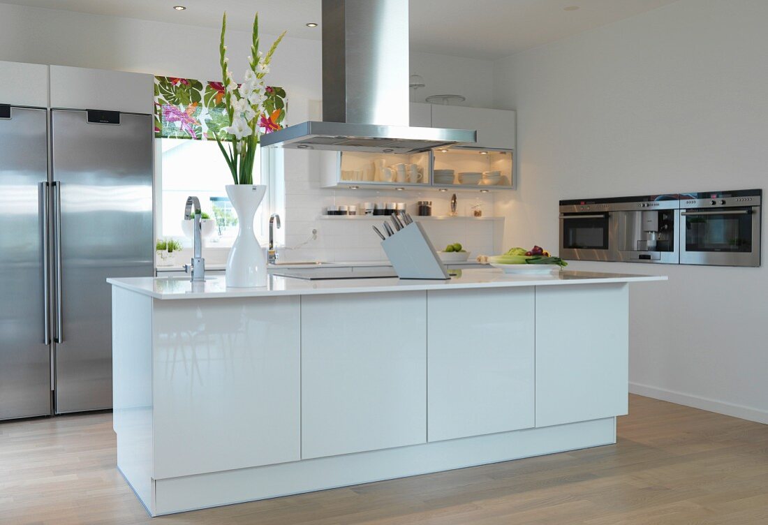 Open-plan designer kitchen with stainless steel appliances and central island counter with extractor hood