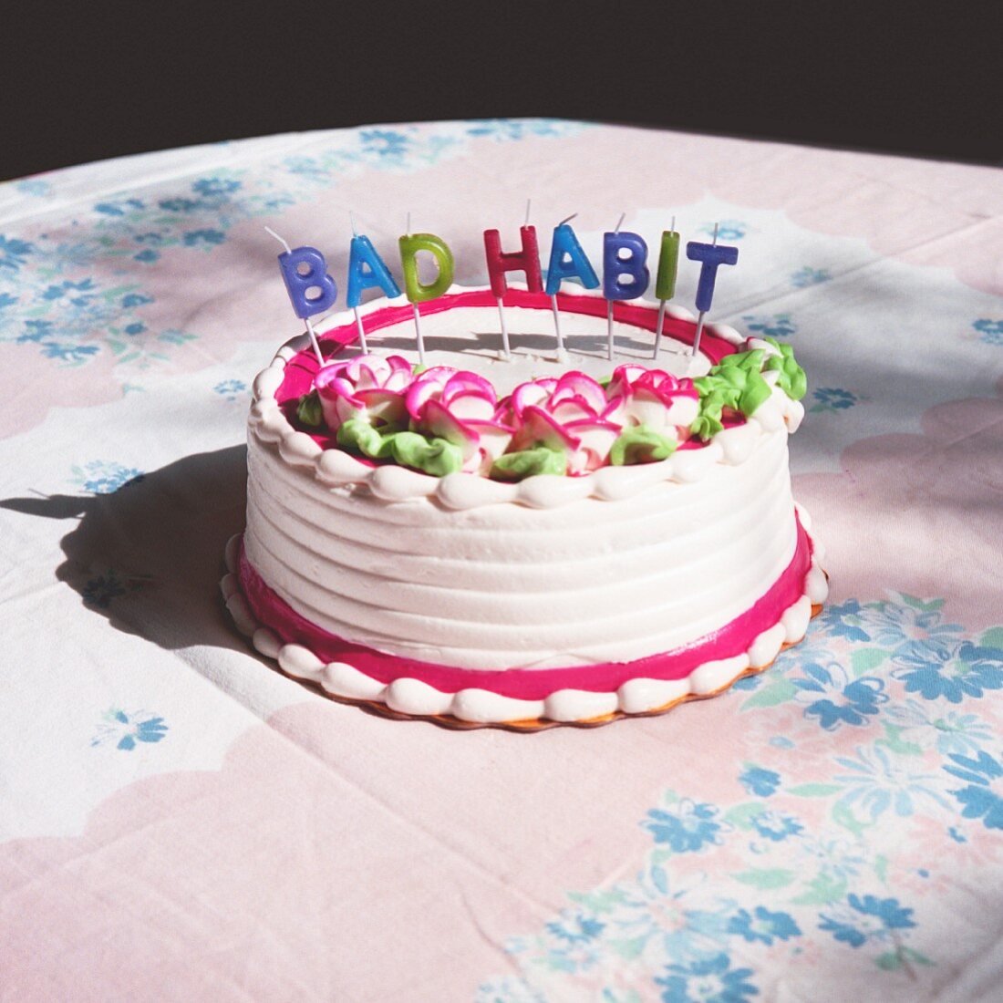 A birthday cake with candles spelling the phrase 'Bad habit'