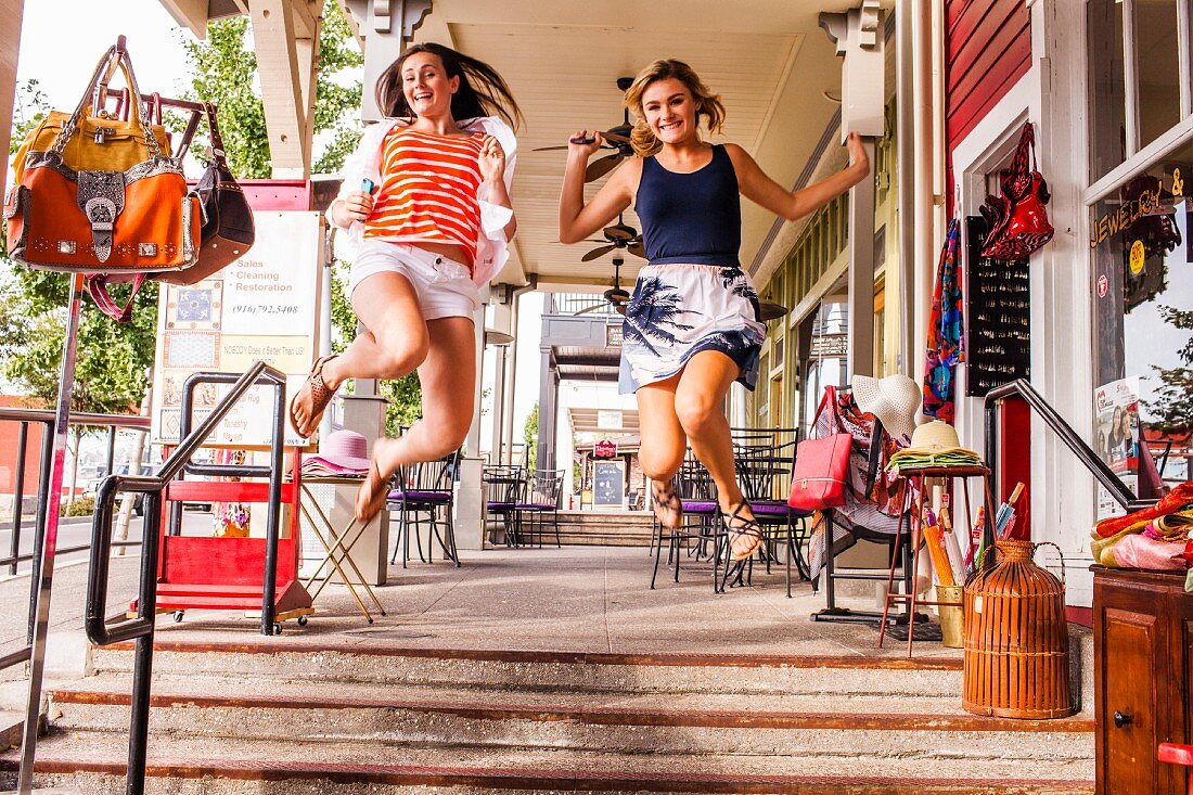 Teenage girls jumping for joy in city