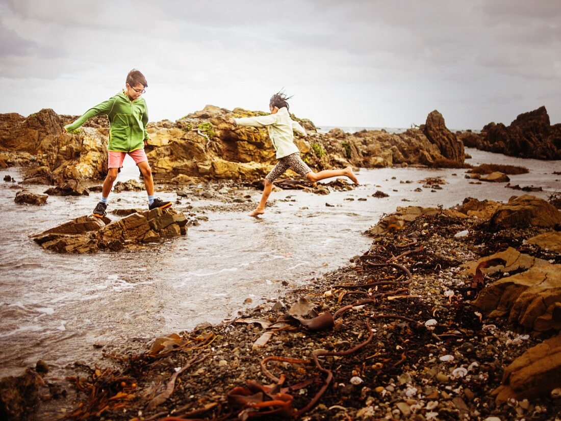 Bruder und Schwester spielen auf felsigem Strand