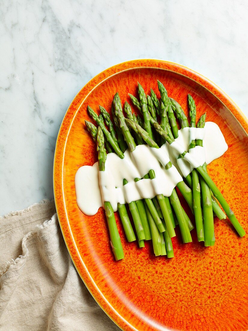 Asparagus with a white sauce on a plate