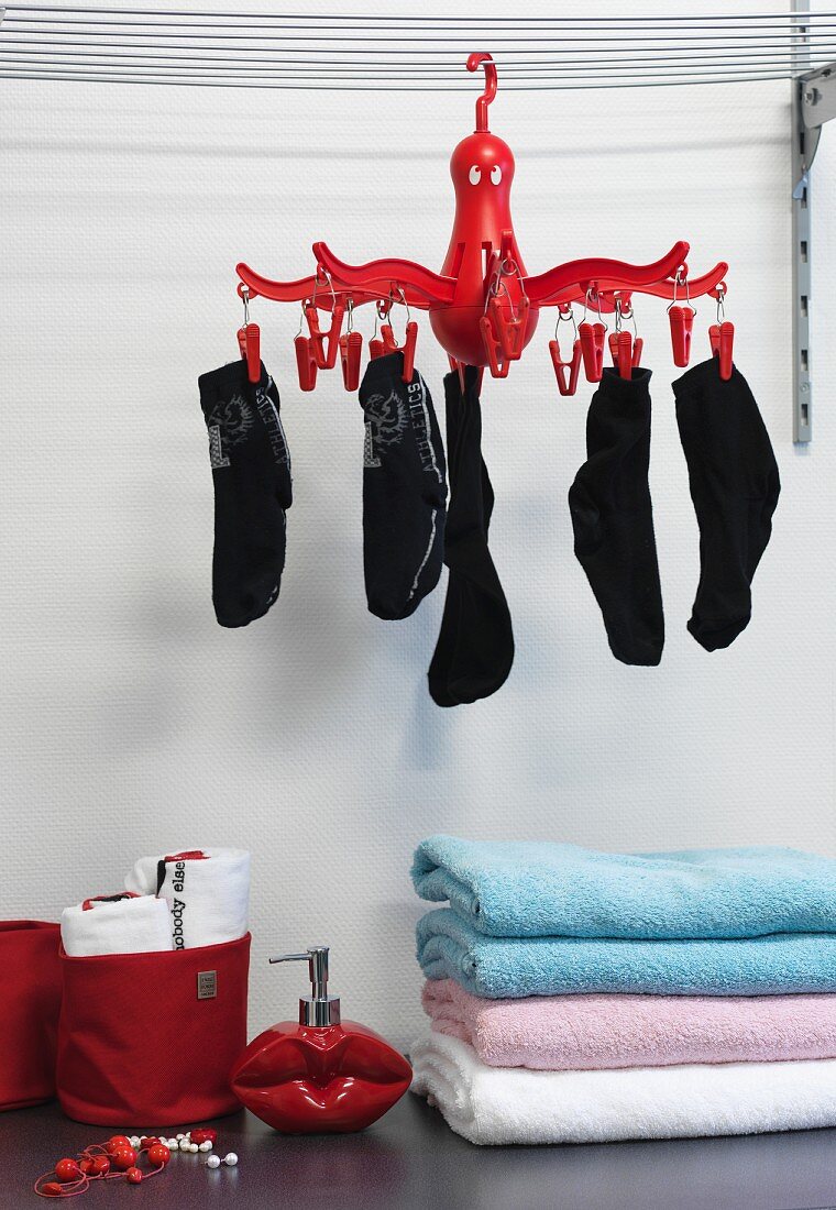 Stacked towels under socks pegged to red, suspended sock dryer