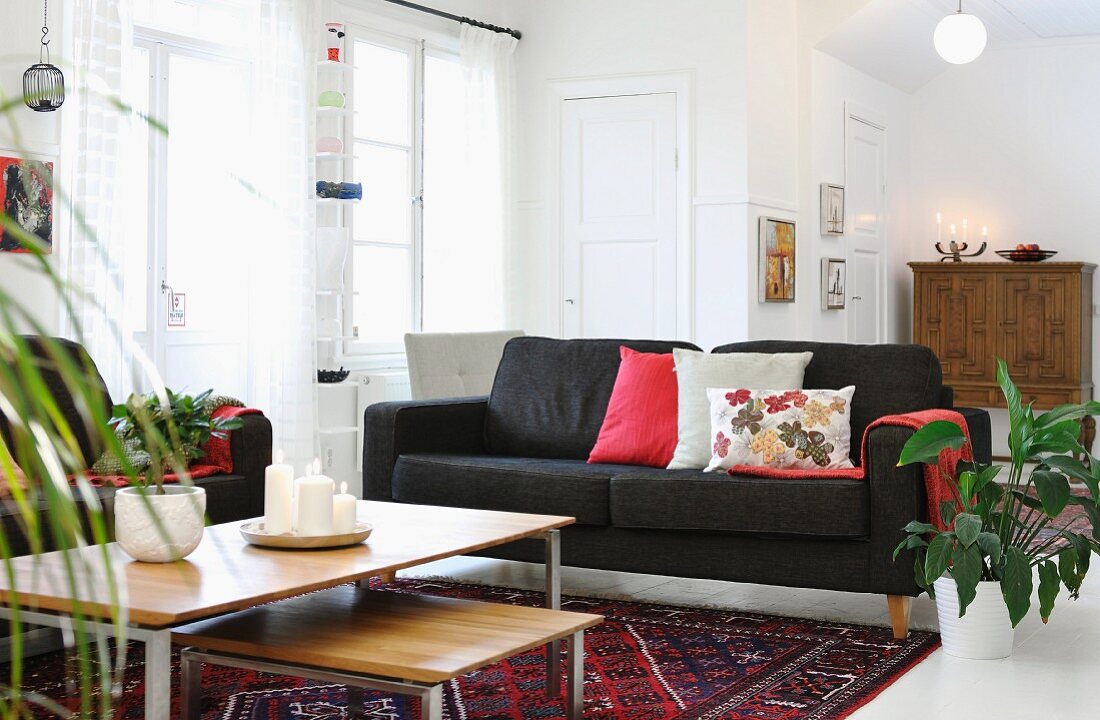 Nest of low coffee tables and black couch in open-plan interior