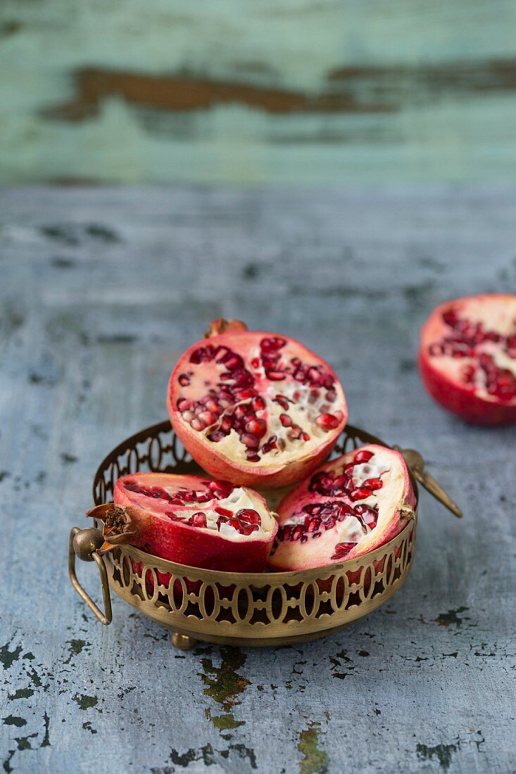 Pomegranate halves in a metal dishes and next to it